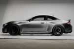 side view of a bmw g87 m2 in a showroom with a body kit made of carbon fibre