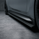 Straight close-up of carbon fibre side skirt running beneath grey BMW M4 G82 door line