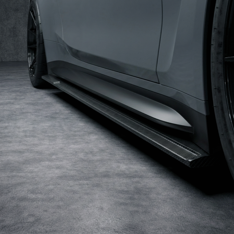 Straight close-up of carbon fibre side skirt running beneath grey BMW M4 G82 door line