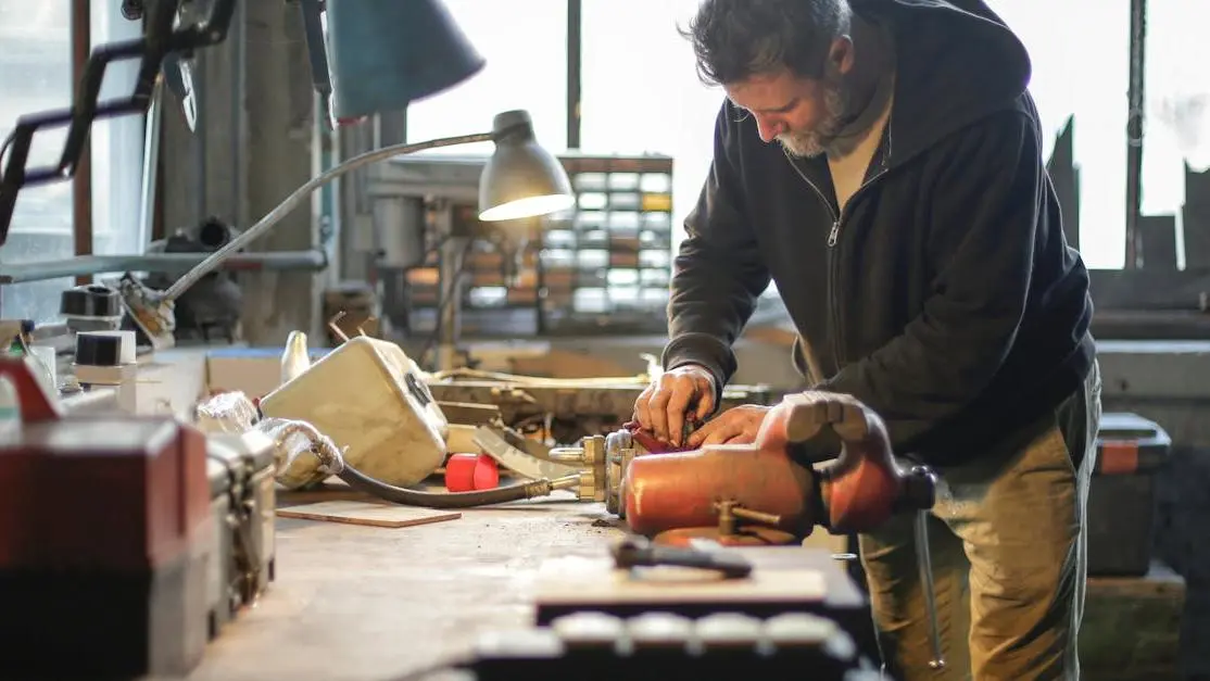 Middle-aged man installing coilovers at workbench in workshop lamplight