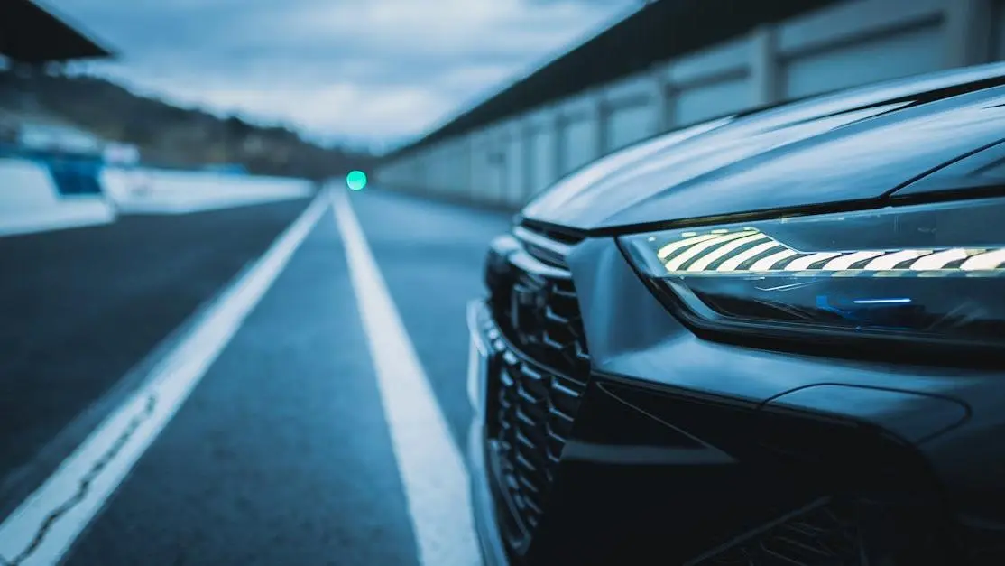 Black car with LED headlights on wet road at dusk, illustrating how to install LED headlights.