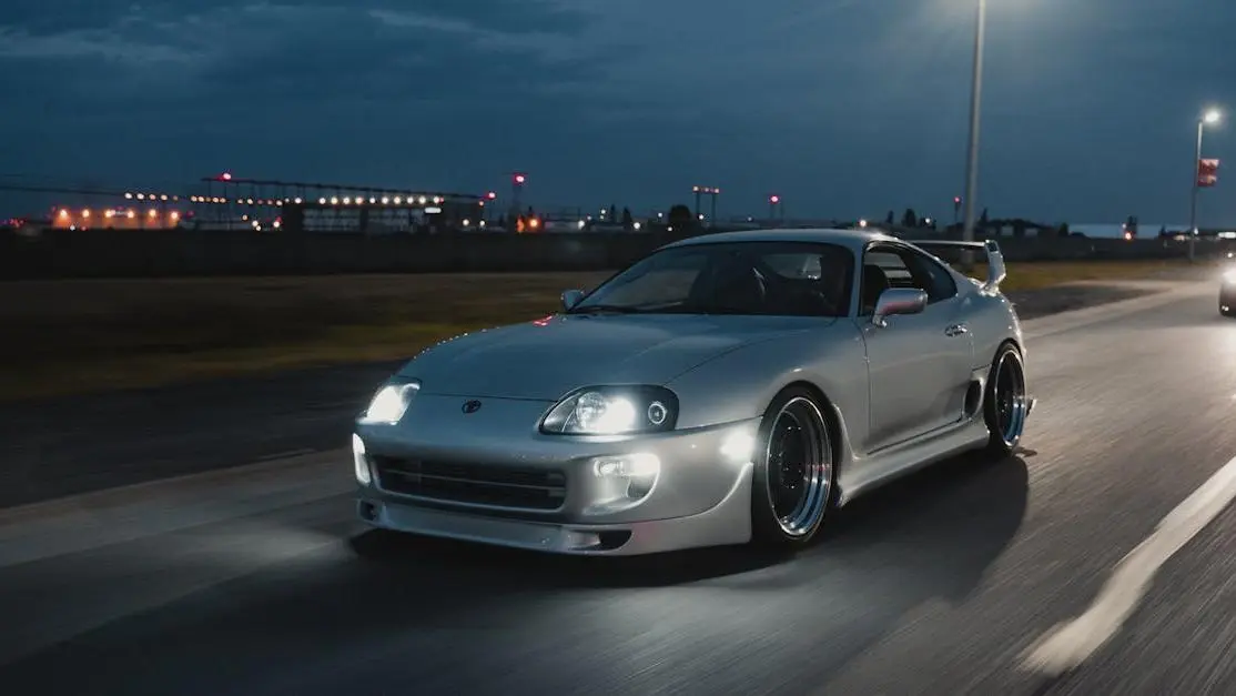 Silver sports car at night with LED vs HID headlights in action, illustrating speed and motion.