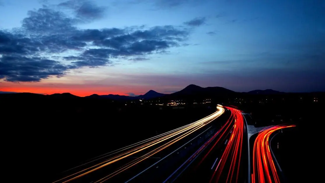 Highway light streaks at twilight in Lovosice, Czechia, with mountains, related to tinted headlights legal.
