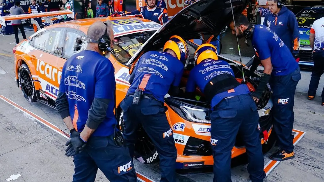 Sports car downpipe tuning by race mechanics in pit lane competition.