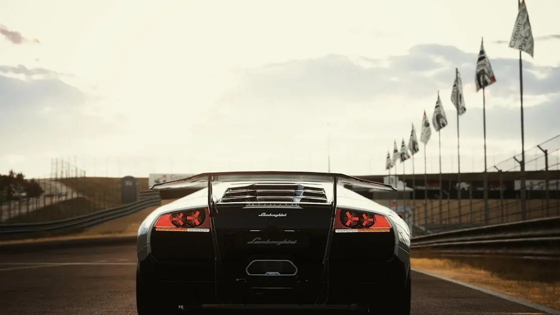 Luxury sports car on racetrack at sunset highlighting spoiler aerodynamics features.