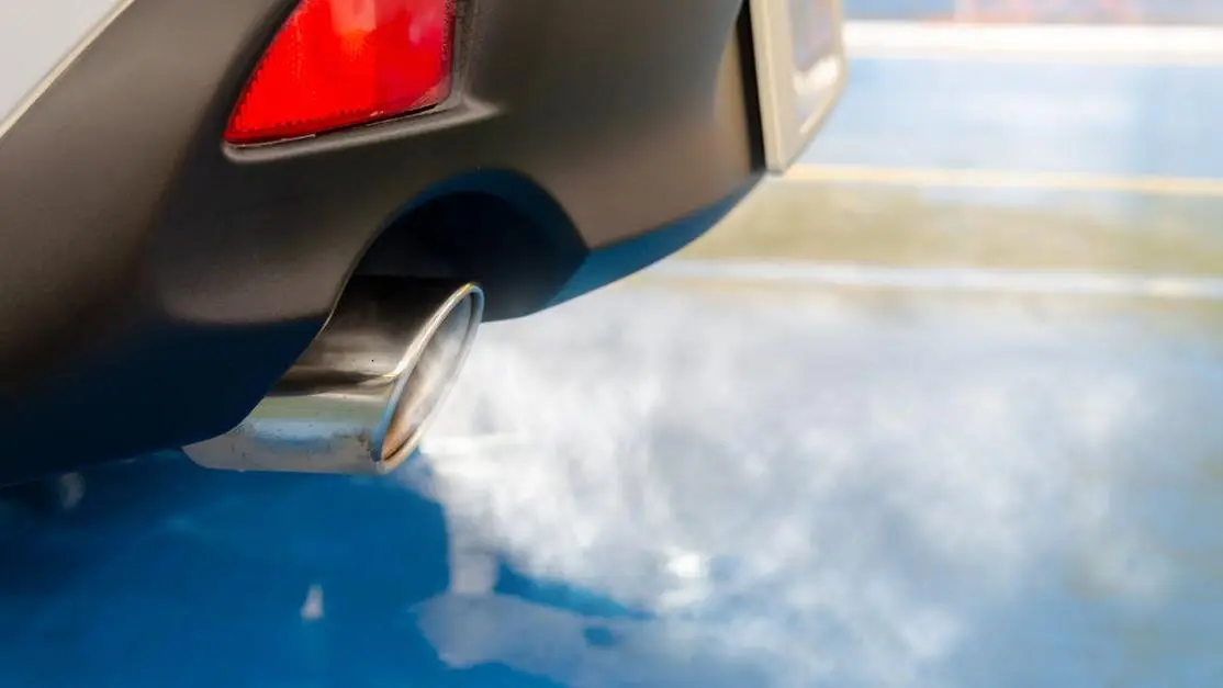 Car exhaust emitting smoke, highlighting straight pipe emissions pollution.