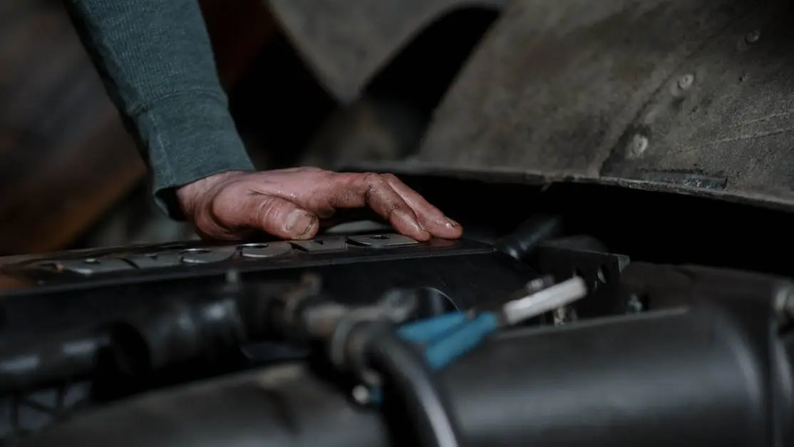 Mechanic inspecting engine for how to read spark plugs for tuning in auto repair shop