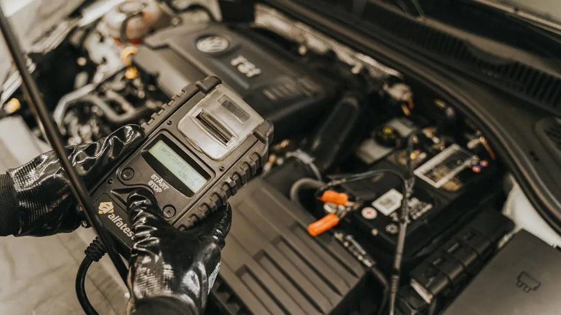 Mechanic tuning car engine for fuel economy using diagnostic tool in auto repair shop.