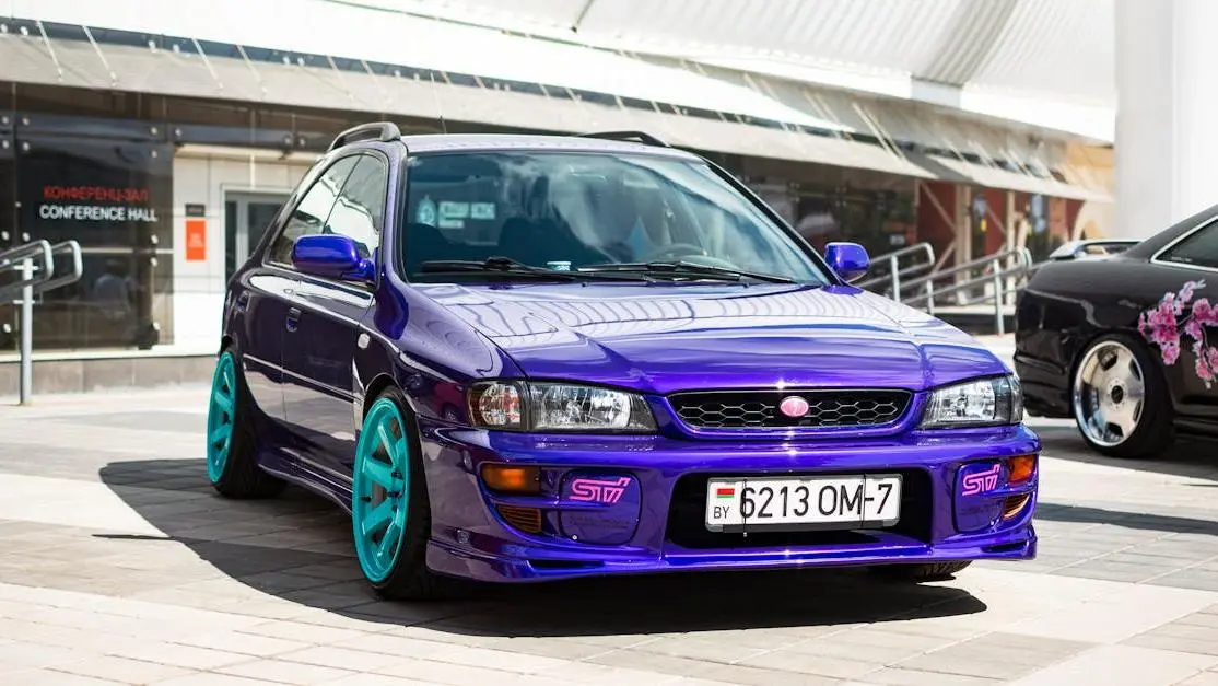 Subaru Impreza with custom teal aftermarket auto wheels parked outdoors
