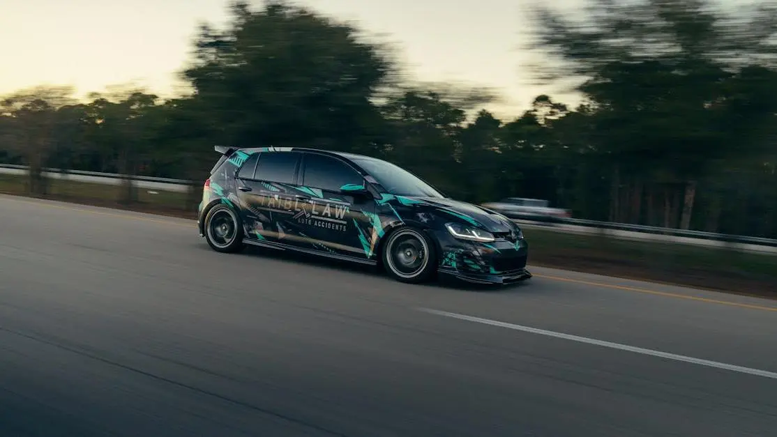 Sleek car with aftermarket modifications driving on highway at dusk, highlighting car modifications.