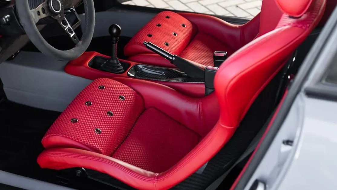 Close-up of red leather and carbon fiber interior with racing car seats and a sporty steering wheel