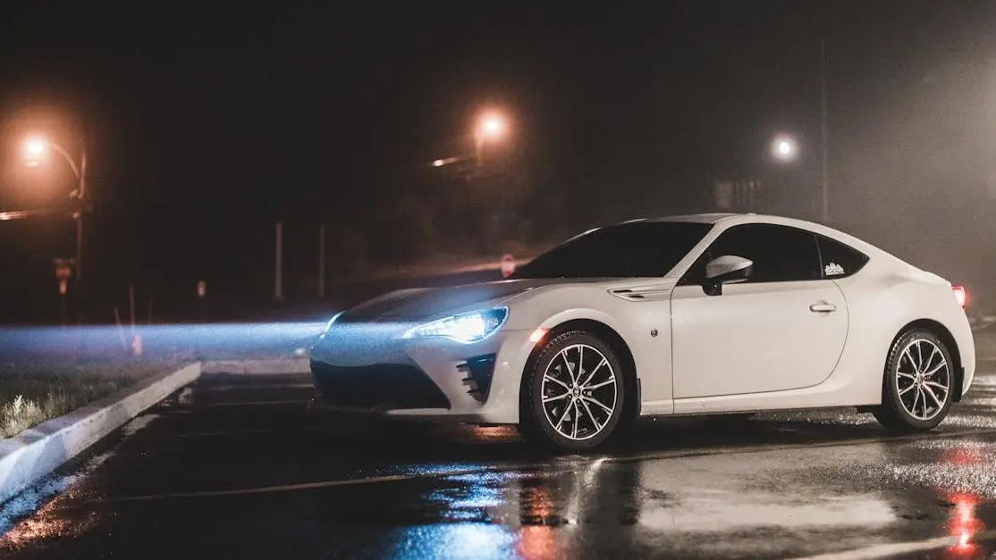 Modern white sports car on wet night street with glowing aftermarket car lights headlights