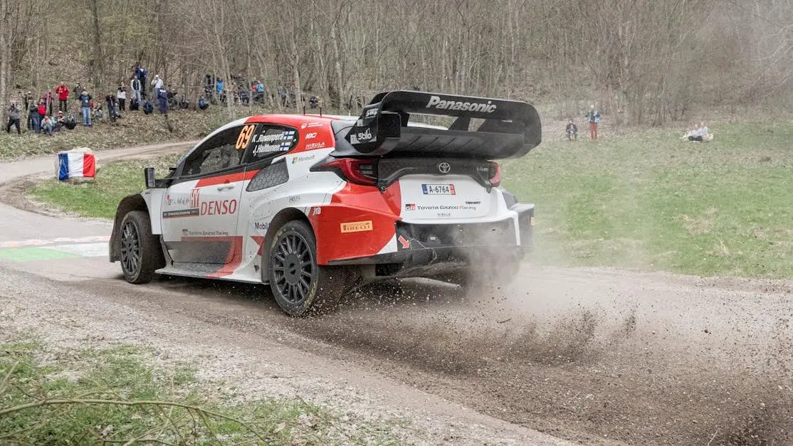 WRC Toyota Yaris on dusty forest track, showcasing auto rally parts in high-speed action