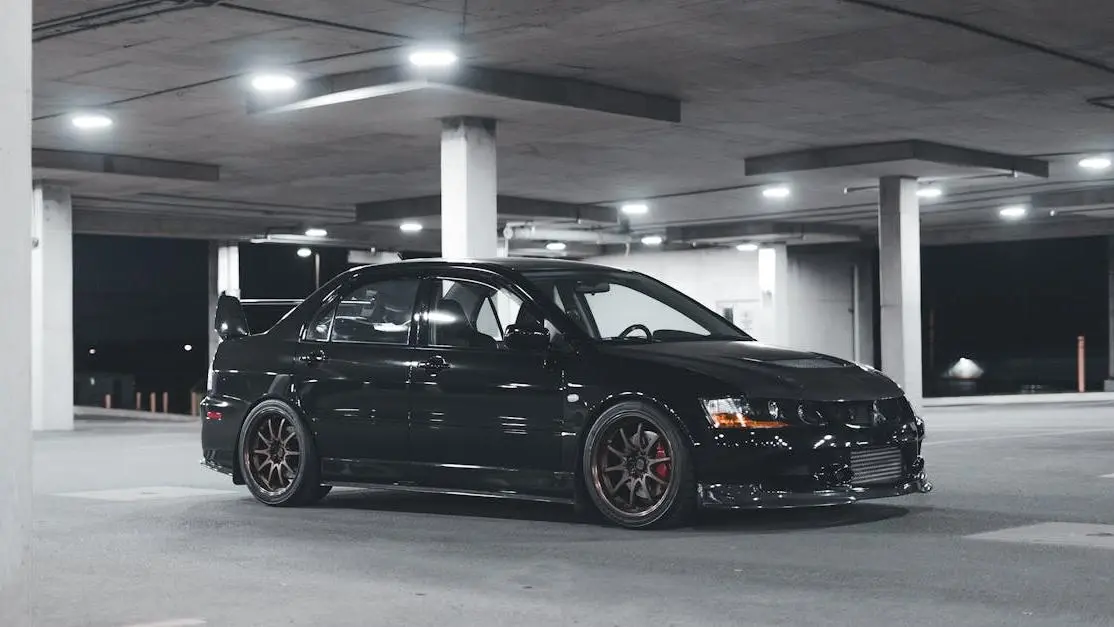 Black Mitsubishi Lancer Evolution in dim garage, showcasing performance auto tuning parts and street style