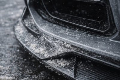 Close-Up Of Carbon Fiber Aero Surface With Winter Road Salt Residue Affecting The Clear Coat And Surface Finish