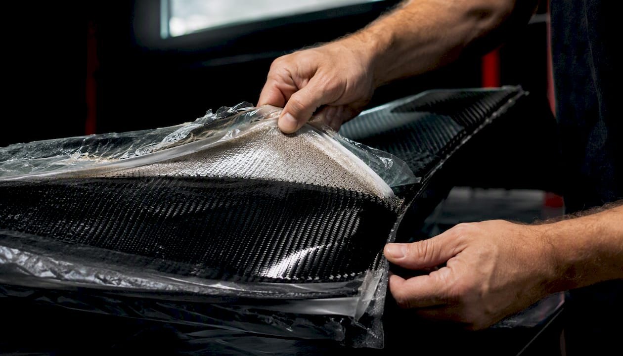 Hands Peeling Bag Material Off Cured Carbon Fiber Panel